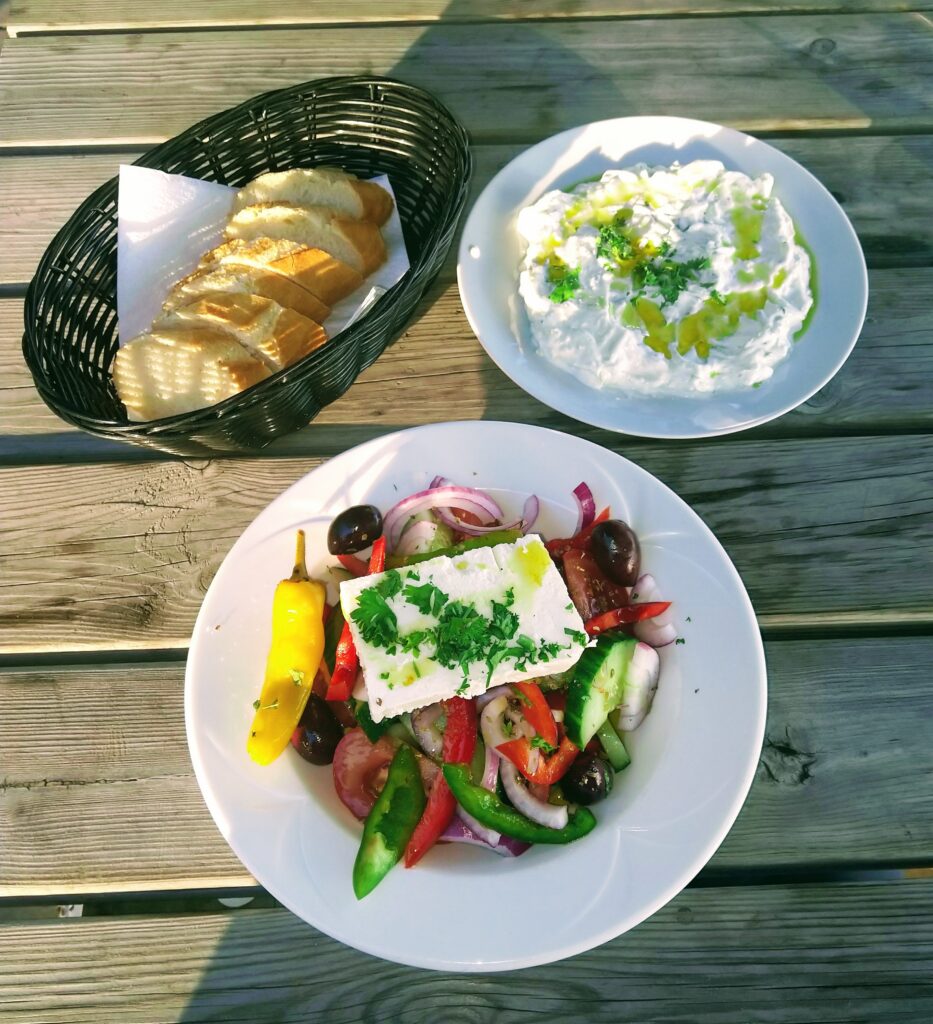 Mesa con ensalada fresca, pan y salsa de yogur al estilo mediterráneo